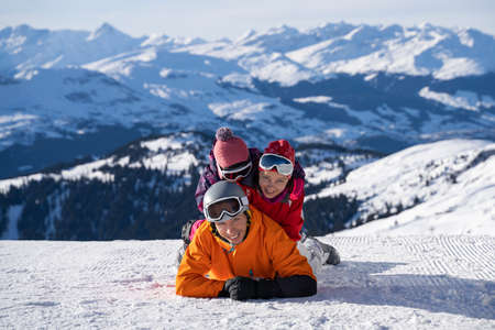 Portrait Of A Happy Family Lying Stacked On Top Of Each Other In Snowの写真素材