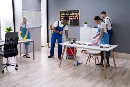 Group Of Janitors In Uniform Cleaning The Office With Cleaning Equipmentの写真素材