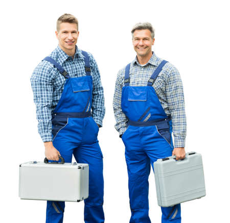 Portrait Of Smiling Two Repairmen Holding Grey Tool Boxes In Hand Against White Backgroundの写真素材