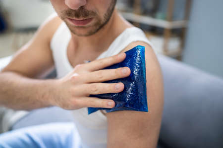 Close-up Of A Man Applying Cool Gel Pack On His Shoulderの写真素材
