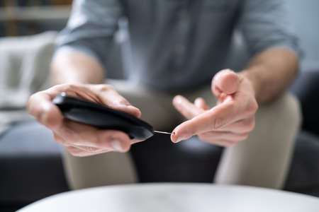 Close-up Of A Man's Hand Testing High Blood Sugar With Glucometerの写真素材