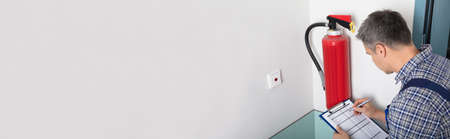 Close-up Of Technician Using Digital Tablet Checking Fire Extinguisherの写真素材