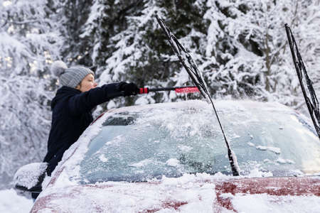 Woman Cleaning Car From Snow After Heavy Snowfallの写真素材