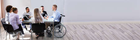 Disabled Male Manager Sitting With His Colleagues At Workplace