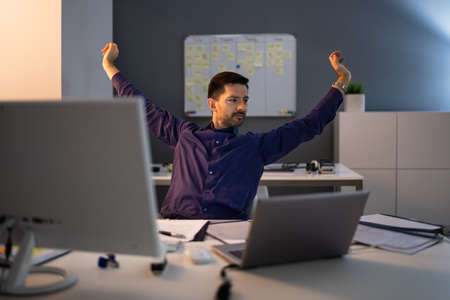 Happy Young Businessman Stretching His Arms In Office