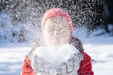 Young Woman In Winter Clothes Blowing Snowの写真素材
