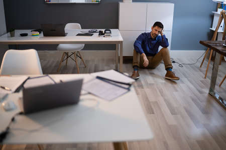 Sad Young Man Sitting At The Floor Of The Room At Officeの写真素材