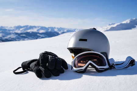 Gloves And Goggles In Snow Against Blurred Mountain Backgroundの写真素材