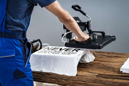 Man Printing On T Shirt In Workshop