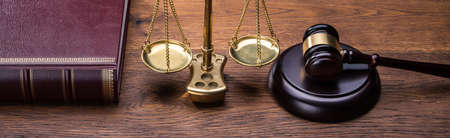 Wooden Gavel With Golden Scale Near Book On Tableの写真素材