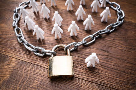 Person Figures Surrounded By Chain And One Person Outside On Wooden Tableの写真素材