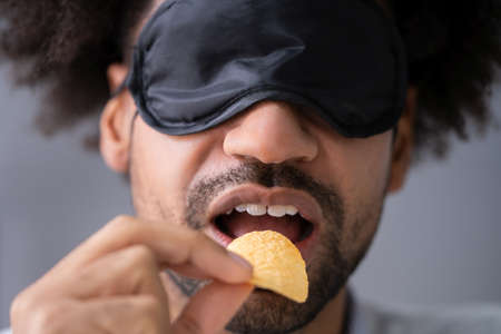 Portrait Of Blindfolded Young Man Testing Foodの写真素材