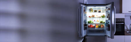 Open Refrigerator Full Of Juice And Fresh Vegetables In Kitchenの写真素材