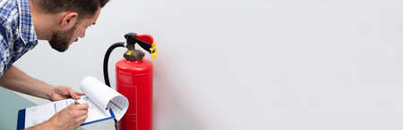 Close-up Of Technician Using Digital Tablet Checking Fire Extinguisherの写真素材