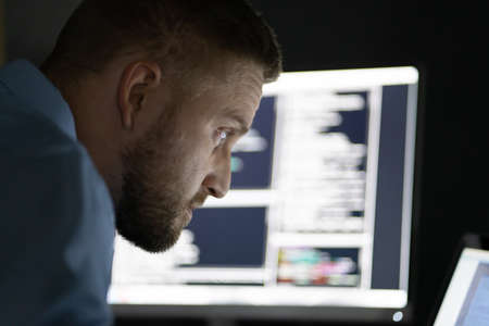Programmer Working Late At Night On Multiple Computer Screens