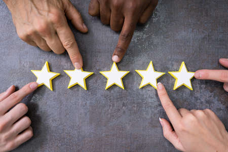 Person Hands Aligning Five Star Rating Icons. High Angle View