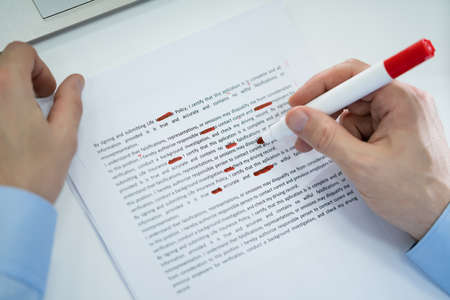 Close-up Of Red Pencil Marking Error During Spellchecking Text On Paper Documentの写真素材