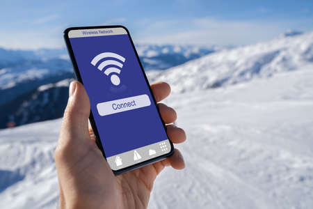Hand Holding Mobile Phone With Wireless Signal In Mountainsの写真素材