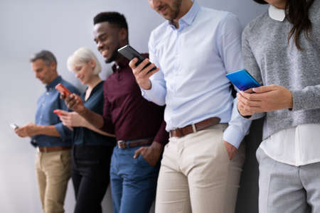 Row Of Diverse Businesspeople Using Phones In Office