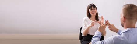 Smiling Young Woman And Man Talking With Sign Language On White Background