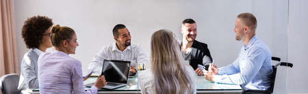 Disabled Manager Sitting With His Colleagues At Workplace