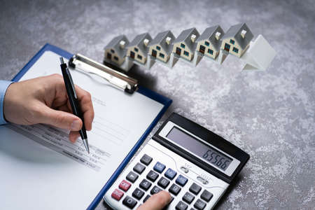 Man Calculating Invoice In Front Of House Models On Increasing Arrow Staircase