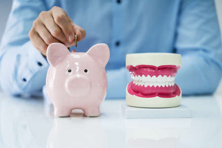 Man Inserting Coin In Piggy Back For Oral Dental Treatmentの写真素材