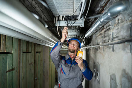 Male Worker Wearing Hard Hat Using Multimeter
