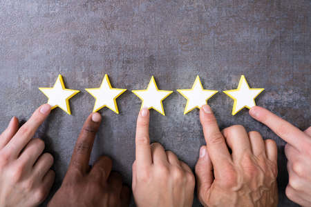 Person Hands Aligning Five Star Rating Icons. High Angle View