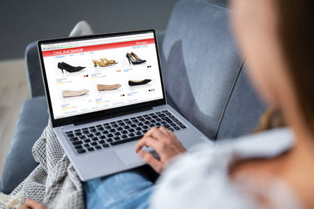 Close-up Of Woman Sitting On Sofa Shopping Footwear's Online On Laptop At Homeの写真素材
