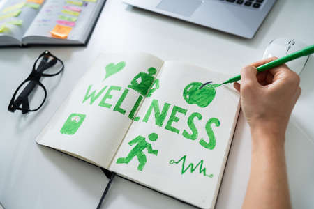 High Angle View Of A Human Hand Drawing Wellness Concept On Notebookの写真素材