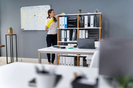 Young Worker Cleaning Desk With Rag In Office
