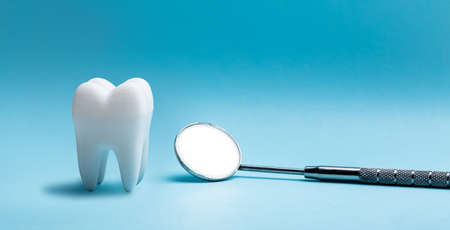Close-up Of White Artificial Tooth And Dental Equipment On Blue Backdrop