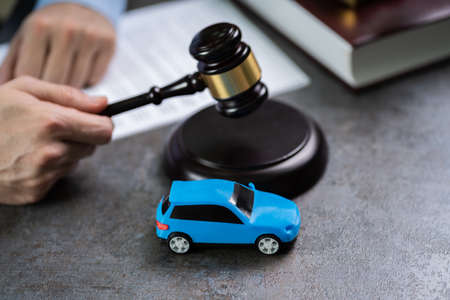 Close-up Of A Small Red Car In Front Of Judge Holding Malletの写真素材