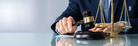 Midsection Of Male Judge With Mallet And Weight Scale At Deskの写真素材