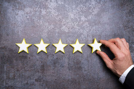 Person's Hand Making Five Star Rating Icon On Desk