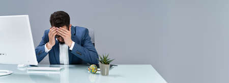 Man Suffering From Headache Working In Officeの写真素材