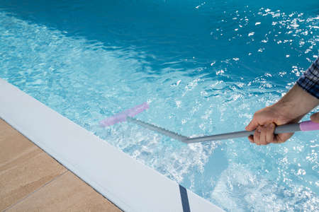 Male Worker In Uniform Cleaning Swimming Poolの写真素材