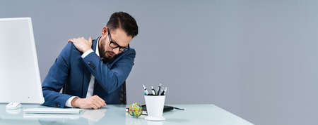 Businessman Suffering From Shoulder Pain At Workplace