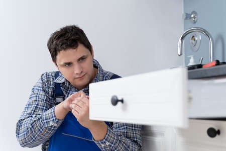 High Angle View Of Male Carpenter Fixing Drawer In Kitchen