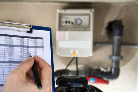 Worker Holding Clipboard Inspecting Water Pump And Pipesの写真素材