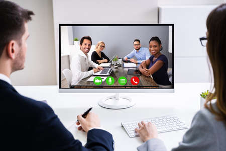 Two Young Businesspeople Video Conferencing On Computer At Office