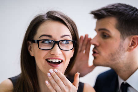Close-up Of Businessman Whispering Into Female Partner's Ear