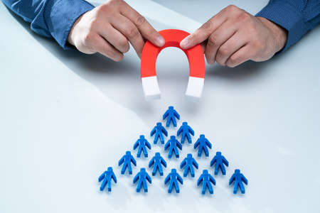 Businessman's Hand Attracting Blue Team With Horseshoe Magnet On White Backgroundの写真素材