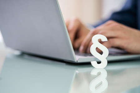 Businessperson's Hand Using Laptop With Paragraph Symbol On Deskの写真素材