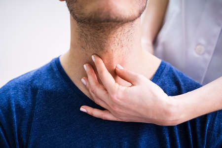 Close-up Of A Doctor's Hand Touching The Throat Of A Male Patient In The Clinic