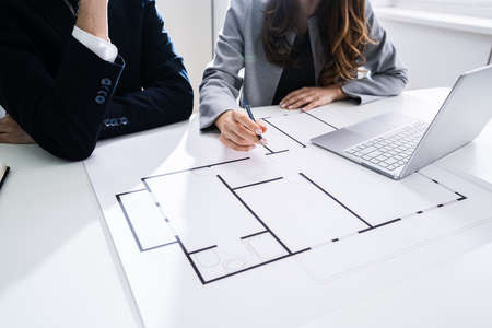 Close-up Of Two Architects Hands Working On Blueprintの写真素材