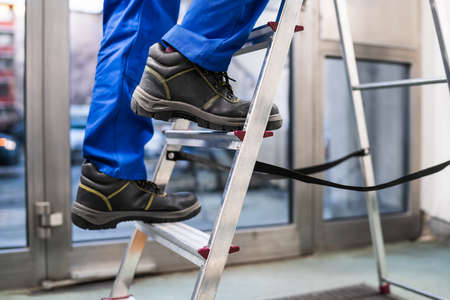 Low Section View Of A Handyman's Foot Climbing Ladder