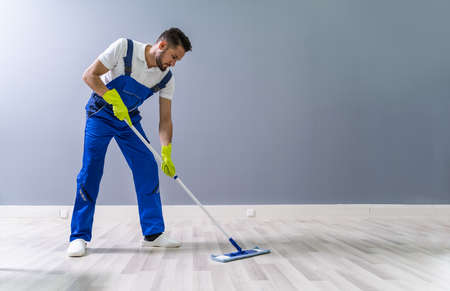 Worker Mopping Floor With Mop In Office