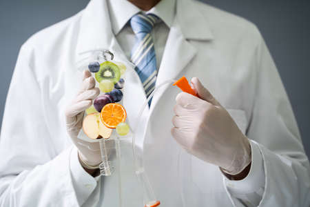 Male Doctor Holding Saline Bag With Fruit Slices Inside In Hospitalの写真素材